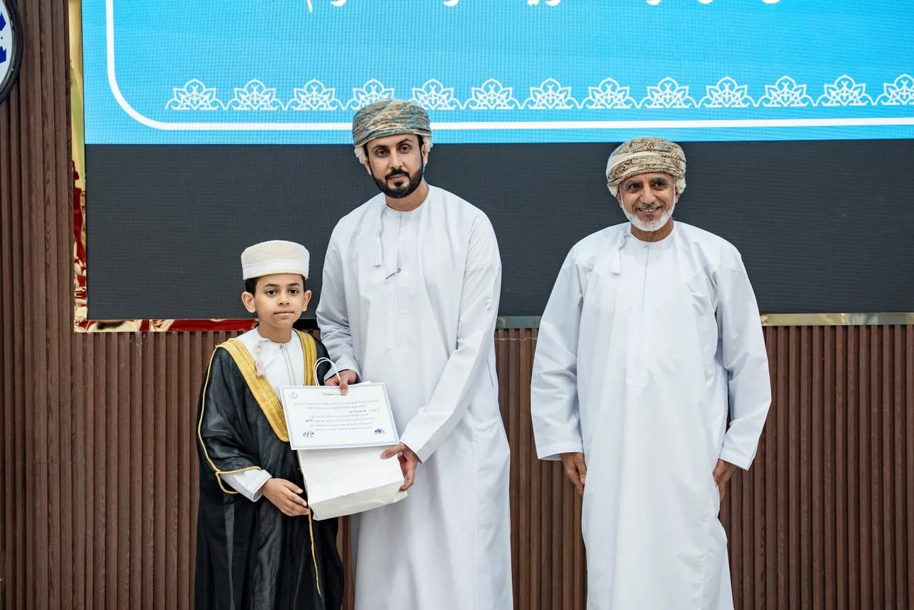 أحد الفائزين يتسلّم شهادة التكريم من راعي الحفل
